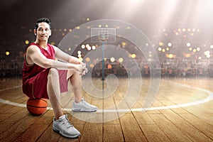 Asian man basketball player sitting on the ball
