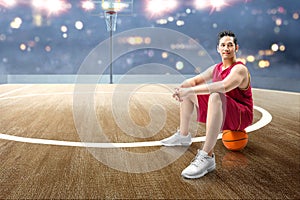 Asian man basketball player sitting on the ball