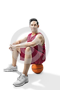 Asian man basketball player sitting on the ball