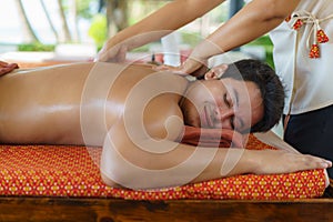 Asian man in beach spa salon getting oil massage near beach and looking happy in Thailand. Spa, resort, beauty and health concept