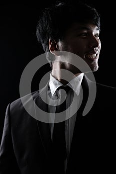 Asian man in black formal suit in the dark