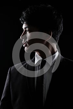 Asian man in black formal suit in the dark