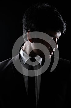 Asian man in black formal suit in the dark