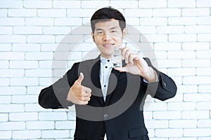 Asian man in black suit hand hold vial of vaccine with trump up