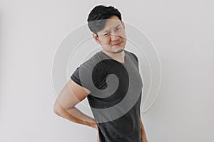 Asian man in black t-shirt feeling sick and hurt of back pain  on white.