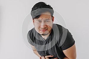 Asian man in black t-shirt feeling sick and stomach ache isolated on white.