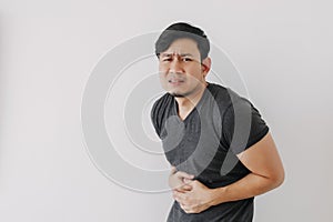 Asian man in black t-shirt feeling sick and stomach ache isolated on white.