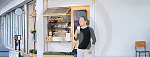 Asian man in the black t-shirt holds the bubble ball ice Milk Tea in front of the shop on the outdoor street footpath