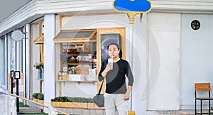 Asian man in the black t-shirt holds the bubble ball ice Milk Tea in front of the shop on the outdoor street footpath