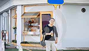 Asian man in the black t-shirt holds the bubble ball ice Milk Tea in front of the shop on the outdoor street footpath