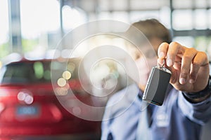 Asian man blurred holding in key car in dealership service maintenance insurance and receives the keys from the customer for send