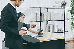 Asian man boss pointing finger to a stressed woman employee in office