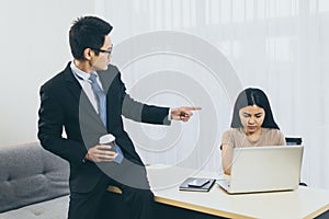 Asian man boss pointing finger to stressed woman employee in office