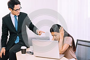 Asian man boss pointing finger to stressed woman employee in office