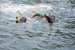 Asian man and Boy wearing a life jacket and scuba diving in the sea