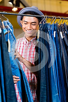 Asian man browsing jeans in fashion store
