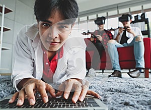 Asian man browsing netbook on floor near gamers