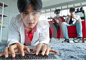 Asian man browsing netbook on floor near gamers