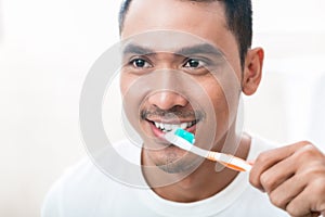 Asian man brushing teeth