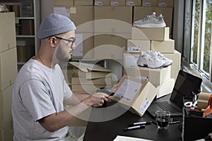 Asian man business owner scanning barcode on delivery parcel. E-commerce male business owner working in factory