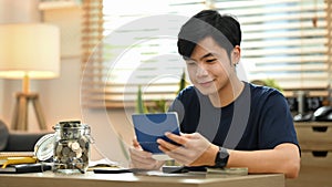 Asian man calculating household finances or taxes on calculator, managing expenses finances concept