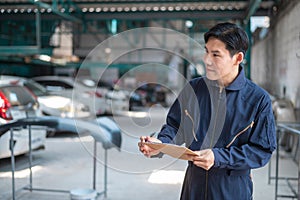 Asian man car mechanic is checking report in auto repair shop