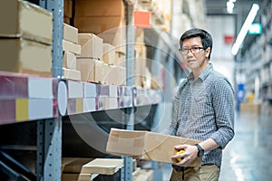 Asian man carrying cardboard box in warehouse