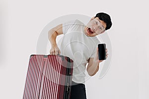 Asian man carrying a suitcase and holding mobile phone, showing application for travel and booking.