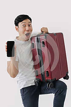 Asian man carrying a suitcase and holding mobile phone, showing application for travel and booking.