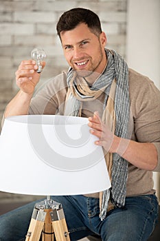 asian man changing light bulb