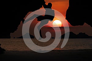 Asian man climbing a cliff by the sea As the sun sets around the islands in the Gulf of Thailand