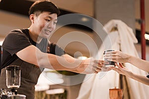 Asian man, coffee maker, handing over a cup of coffee Served to female customers counter