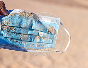 Used face mask on the beach with outdoor sun lighting.