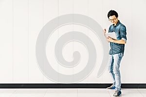 Asian man or college student using digital tablet cheering celebrate success, copy space on white wall background