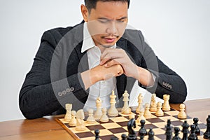 Asian man concentrates on taking step while playing chess