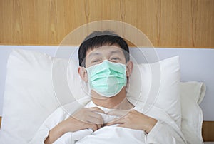 Asian man coughing and suffering in medical mask inside bedroom.China Coronavirus outbreak