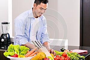 Asian man cutting vegetables and salad