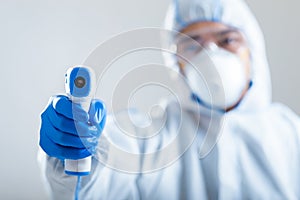 Asian man directs infrared thermometer on camera photo