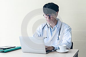 Asian man doctor is using a notebook computer, In search of information And write a report about the patient`s condition