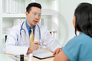 Asian man doctor and woman patient are discussing consultation about symptom problem diagnosis of disease talk to the patient