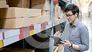 Asian man doing stocktaking on tablet in warehouse