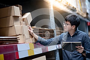 Asian man doing stocktaking on tablet in warehouse