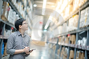 Asian man doing stocktaking by using tablet in warehouse