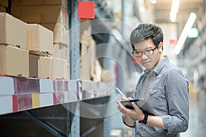 Asian man doing stocktaking by using tablet in warehouse