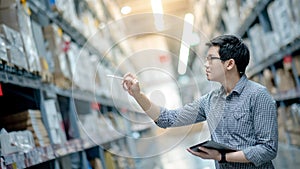 Asian man doing stocktaking by using tablet in warehouse