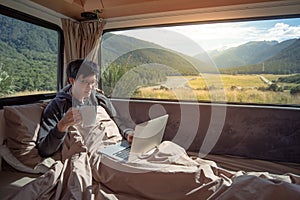 Asian man drinking coffee in camper van