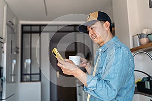 Asian man drinking coffee and using mobile at home