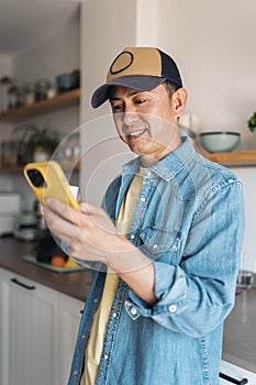 Asian man drinking coffee and using mobile at home