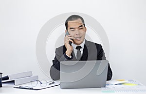 Asian man employee talking on the phone and working in a laptop with a smiling face, Office staff work and telephone conversations