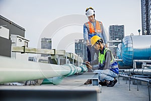 Asian man engineer holding tablet working at rooftop building construction. Male technician worker working checking hvac of office
